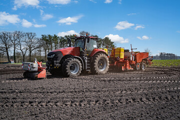 Modernes Kartoffellegegerät mit Traktor im Frühjahr auf dem Kartoffelfeld im Einsatz. 