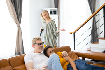 Girl cleaning home. Caucasian daughter teenage doing housekeeping clean house while father and mother lazy watching smart TV sitting on sofa in living room at home.