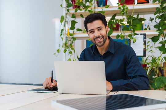 Portrait of smiling businessman with digital tablet, laptop and solar panel on desk