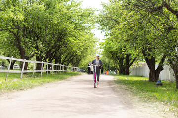 Cute teenager girl riding electric kick scooter in the park