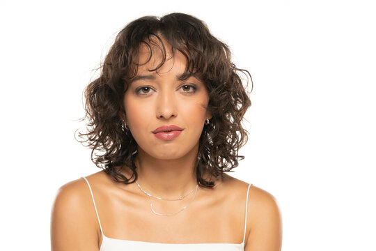 Young dark skinned woman with makeup and wavy hair posing on a white background