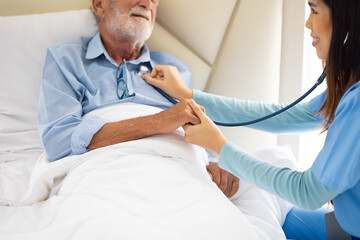 Obraz premium Closeup hand Female Nurse use stethoscope. Professional caregiver nursing visit elderly patient at home. Nurse assisting senior patient at nursing home.