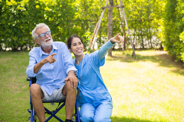 Female Nurse assisting senior patient at nursing home. Home care. disabled old man with walker at backyard. Professional caregiver nursing home