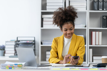 African American businesswoman Working on mobile phone and laptop computer to view data and use in business dealings working tax, accounting, statistics and analytic research concept.