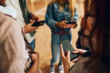 Close up of students using their cell phones in hallway at high school.