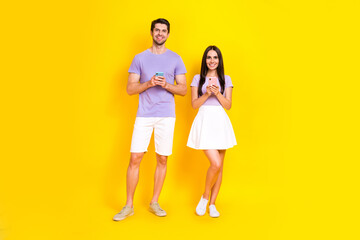 Full length photo of lovely young lady guy hold device chatting message matches wear trendy purple look isolated on yellow color background