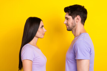 Fototapeta premium Profile portrait of two calm concentrated people look each other isolated on yellow color background