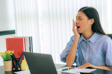 Attractive asian businesswoman feeling tired from overwork affecting health, extending breaks to relieve stress in the concept of remote work from home or burnout disease.