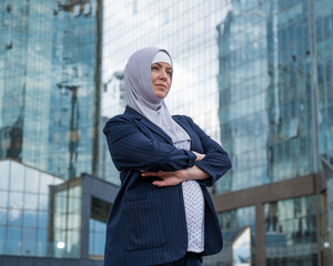 Portrait of a pregnant business woman in a hijab and a suit with crossed arms on her chest outdoors. - Powered by Adobe