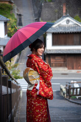 The portrait of attractive Asian woman wearing traditional Japanese Kimono with umbrella in Old town, Kitsuki, Japan