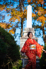 Attractive Asian portrait of smiling woman wearing kimono in Park in Autumn season, Japan