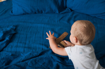 Toddler boy plays with airplane on bed close-up.