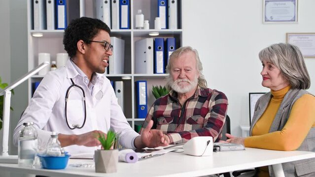 medical consultation, elderly pensioners at reception of a black male doctor in office