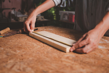 Female use tape measure to assemble wooden pieces. Professional carpenter at work measuring wooden planks.