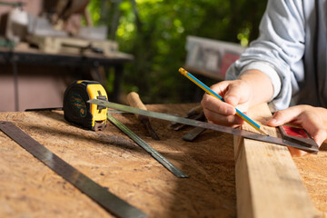 Female hands using a try square to check that the woodworking corners are square with a set...