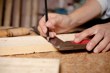 Female hands using a try square to check that the woodworking corners are square with a set...