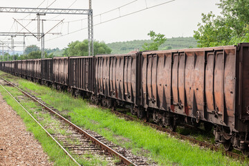 Fototapeta na wymiar Coal train made of Open Wagons, also called Gondola wagons, rusty, waiting on a freight railway station, half abandoned, in Serbia, in a former cargo and industrial hub of the region.