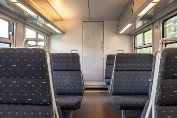 Row of Empty seats in a regional train with an aisle, European style, on a travel in Belgium, belonging to Belgian railways, currently being modernized to decrease travel times.