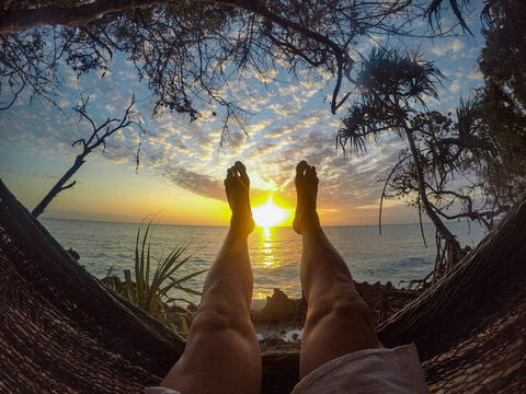 person lying in a hammock with feet in the air on an African beach before dinner