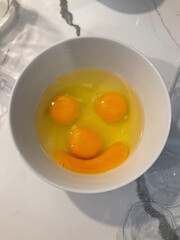 Smiling egg yolks in a white bowl.