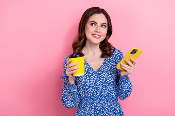 Portrait of charming lovely person hold smart phone fresh coffee cup look empty space isolated on pink color background