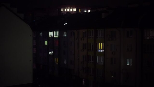 Urban residential building on dark night with flashing emergency lights reflecting on wall. Wide shot house in city in Ukraine during blackout