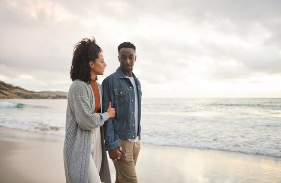 Young multiethnic couple holding hands and walking on a sandy beach - Powered by Adobe