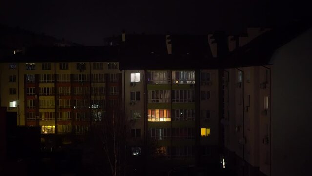 Wide shot urban house at dark night in Kiev Ukraine during blackout shutdown. Residential building in city in war zone