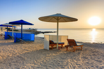 Sun loungers with umbrellas on the beach in Marsa Alam at sunrise, Egypt