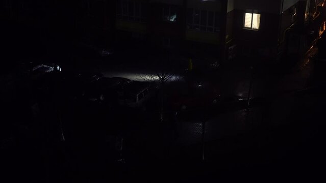 High angle view dark night during blackout in city with pedestrians walking with flashlights. Darkness outdoors in war zone in Ukraine