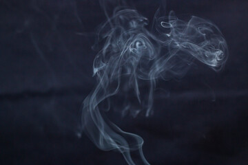 A lot of incense smoke swirls on a dark background	
