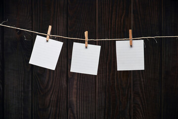 Three white lined note sheets pinned on the rustic craft rope on the background of old wooden planks