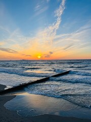 Orange sunset at the sea, sunlight in the sky, evening sun reflection on the sea surface, sandy coastline 