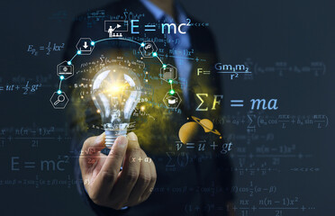 The student held a light bulb and physics equations floated around him, showing that learning helped solve problems and find solutions. physical equation concept. albert einstein and sir isaac newton.