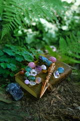 Ritual knife, set of minerals and magic witch book in forest, blurred natural green background. Phurba is three-sided knife, traditionally of Indo-Tibetan Buddhism for esoteric spiritual practice