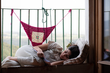 girl on balcony reading relaxed, woman in her twenties in rural house relaxing with a book,...