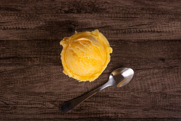 Tasty yellow ice cream served in a white china pot next to a spoon. Top photography. Ice cream parlors and ice cream parlours.