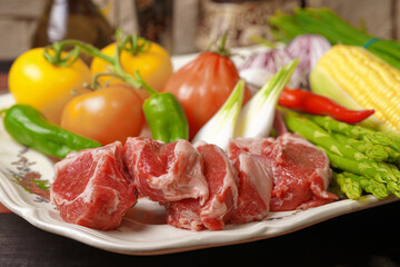 The rack of lamb lies on a beautiful platter with asparagus and various vegetables. Homemade food.