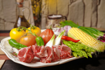 The rack of lamb lies on a beautiful platter with asparagus and various vegetables. Homemade food.