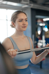  young girl in a tracksuit holds the bar of her pants before an exercise in the gym