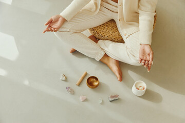 Top view of woman meditating with Tibetan singing bowl and gemstones.