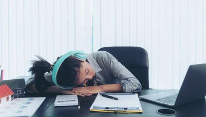 Exhausted and tired young adult office worker falling asleep on desk because of overtime work...