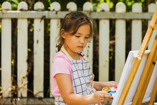 Young artist girl painting on canvas outdoors, Kids Artist