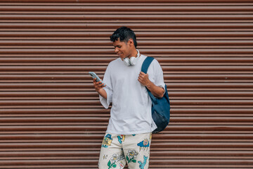 young latino man in the street looking at the mobile phone