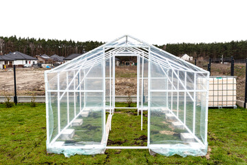 Fototapeta premium Assembling a home greenhouse from an aluminum frame and thick foil..