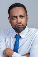 Grumpy black business man wearing a shirt and tie frowning with his arms folded