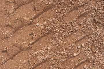 Footprint of car tire tread in a sand gravel road texture. Country road textured background. Backdrop for various ideas. Small stones land. Abstract sandy rough surface. Trendy effect. No people. Tyre