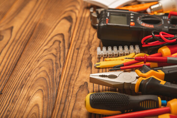 Electrician equipment on brown background with copy space.Top view.Electrician tool set.Multimeter, tester,screwdrivers,cutters,duct tape,lamps,tape measure and wires.Flet lay. © Avocado_studio