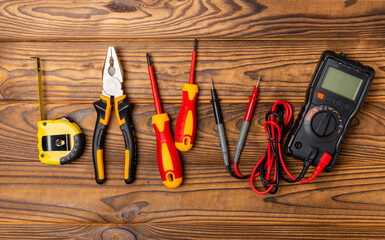 Electrician equipment on brown background with copy space.Top view.Electrician tool set.Multimeter, tester,screwdrivers,cutters,duct tape,lamps,tape measure and wires.Flet lay.