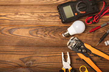 Electrician equipment on brown background with copy space.Top view.Electrician tool set.Multimeter, tester,screwdrivers,cutters,duct tape,lamps,tape measure and wires.Flet lay. © Avocado_studio